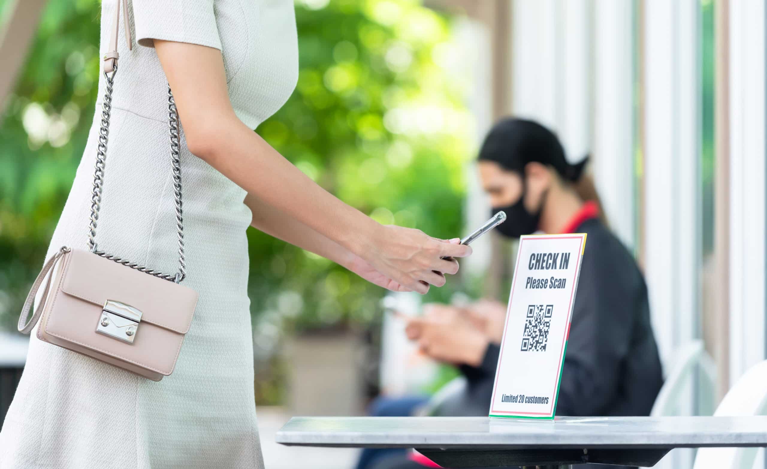 woman using phone to scan a qr code and check in